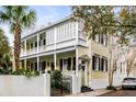 Beautiful two-story home with a yellow exterior, a white porch, black shutters, and landscaping at 25 Logan St, Charleston, SC 29401