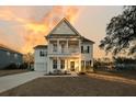 Two-story home boasts double porches, symmetrical design, and sunset sky at 3213 Great Egret Dr, Johns Island, SC 29455