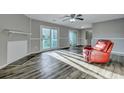 Bright living room featuring wood floors, a cozy red armchair, and sliding glass doors to the outside at 6275 Rolling Fork Rd # C, North Charleston, SC 29406