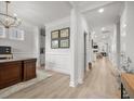 Elegant hallway featuring light wood floors, decorative wainscoting, crown moulding and a view into the living spaces at 641 Sienna Way, Summerville, SC 29486