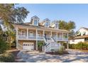 Beautiful raised home featuring an inviting front porch, symmetrical design, and convenient garage access at 7 Seahorse Ct, Isle of Palms, SC 29451