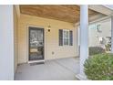 Covered porch featuring a stylish light fixture, neutral siding, and a black-trimmed glass front door at 8475 Athens Way, North Charleston, SC 29420