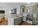 Well-appointed kitchen with stainless steel appliances, granite countertops, tile backsplash, and green cabinetry at 130 River Landing Dr # 4209, Charleston, SC 29492