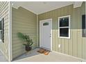 Charming front porch with olive green vinyl siding, a white door, and decorative plants welcoming guests at 1738 N N Hwy 52, Bonneau, SC 29431