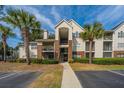 Condo complex featuring palm trees, neutral siding, and brick accents under a blue sky at 2011 N Highway 17 # 1400H, Mount Pleasant, SC 29466