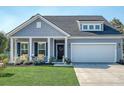 Beautiful blue home with a manicured lawn, welcoming front porch, and attached two car garage at 3278 Great Egret Dr, Johns Island, SC 29455