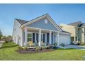 Charming home with a well-kept lawn, flowering shrubs, and an inviting front porch with yellow chairs at 3278 Great Egret Dr, Johns Island, SC 29455