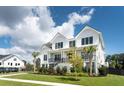 Elegant raised white home showcasing landscaped yard, black trim, and inviting staircase at 509 Seven Farms Dr, Charleston, SC 29492