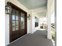 Inviting front porch featuring wooden floors, lantern lighting, and double doors at 509 Seven Farms Dr, Charleston, SC 29492