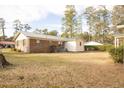 Spacious backyard view featuring a brick home, with the lawn covered in dormant leaves at 105 Pinewood St, Walterboro, SC 29488