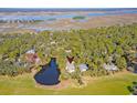 An aerial view shows the house sitting next to a pond surrounded by lush green trees and golf course at 31 Berkshire Hall, Kiawah Island, SC 29455
