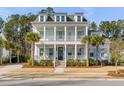 Stunning two-story white home boasts a charming double porch and lovely front yard with mature palm trees at 3699 Goodwater St, Mount Pleasant, SC 29466