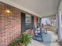 Close-up of the cozy front porch with brick wall, featuring rocking chairs and plants, perfect for enjoying quiet moments at 4869 Habersham Ln, Summerville, SC 29485