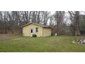 A yellow outbuilding, with a brick wall and a well pump on a lawn at 1097 Murrell Block Dr, Pineville, SC 29468