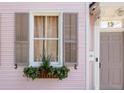 Close-up of a window box and shutters on a pink house with a gray front door and the number 12 at 12 Percy St, Charleston, SC 29403