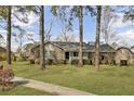 Traditional brick home featuring a cozy front porch and lush green lawn with mature trees at 1205 Scotch Pine Ln, Ladson, SC 29456