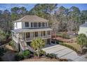 Beautiful two-story home with a double porch, a long driveway, and lush landscaping, enveloped by towering trees at 3575 Holmgren St, Mount Pleasant, SC 29466