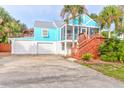 A quaint blue home with a garage and wooden stairs leading to a screened porch at 5 25Th Ave, Isle of Palms, SC 29451
