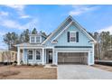 Charming light blue home featuring an attached two-car garage, a covered porch, and a gabled roof at 429 Grove End Rd, Moncks Corner, SC 29461