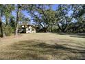 Expansive backyard with mature trees offering ample space, with outbuildings and privacy fencing on property line at 1042 Chambers Ln, Mount Pleasant, SC 29464