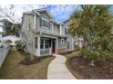 Inviting two-story home with a red front door, covered porch, manicured lawn, and mature trees at 1588 Grey Marsh Rd, Mount Pleasant, SC 29466