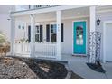 Close-up of a charming covered front porch with a bright blue door, white railings, and decorative plants at 415 Ribiero Dr, Summerville, SC 29486
