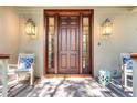 Elegant front entrance featuring a wood door, decorative sconces, and cozy seating area on the porch at 57 Goldenrod Ct, Kiawah Island, SC 29455