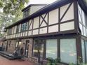 Rear exterior view of Tudor-style home, showcasing brickwork, windows, and deck at 104 Legend Oaks Way, Summerville, SC 29485