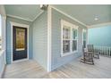 Cozy front porch featuring rocking chairs, light blue siding, and a glass-paneled front door at 1118 John Mcenery Rd, Charleston, SC 29412
