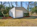 Spacious outbuilding with white door provides ample storage space, nestled among mature trees and green grass at 1217 Bamboo Dr, Charleston, SC 29407