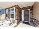 Inviting front porch with stone accents, rocking chairs, and a stylish front door at 123 Lakelyn Rd, Moncks Corner, SC 29461
