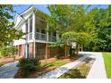 Side view of elevated home, showcasing the screened porch, lush trees, and quaint brick foundation at 1717 Rivertowne Country Club Dr, Mount Pleasant, SC 29466