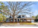 Charming two-story home featuring a basketball hoop, picket fence, brick accents, and mature trees at 74 6Th Ave, Charleston, SC 29403