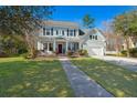 Charming two-story home with blue siding, black shutters, covered porch, manicured lawn, and attached two-car garage at 107 Plank Ct, Summerville, SC 29485