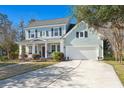 Charming two-story home with blue siding, black shutters, covered porch, manicured lawn, and attached two-car garage at 107 Plank Ct, Summerville, SC 29485