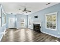 Light-filled living room features light blue walls, a cozy fireplace, ceiling fan and beautiful flooring at 129 E Hartwick Ln, Goose Creek, SC 29445