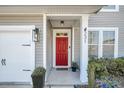 Close-up of a red front door with sidelights, a storm door, and decorative plants at 231 Laurel Crest Way, Summerville, SC 29486
