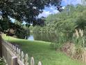 Scenic backyard featuring a tranquil pond view and lush greenery, enhanced by the frame of a white picket fence at 613 Salterton St, Summerville, SC 29485