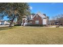 Beautiful brick home featuring a welcoming front porch and lush green lawn at 8696 Spring Chapel Ln, North Charleston, SC 29420