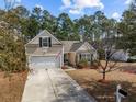 Inviting home featuring a one car garage, American flag, neutral siding and mature trees at 9021 Robins Nest Way, Summerville, SC 29485