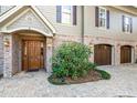 Elegant entryway with a wood door, brick accents, and manicured shrubbery at 176 Marsh Hawk Ln, Kiawah Island, SC 29455