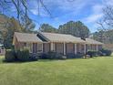 Traditional brick home with a covered entry, complemented by mature trees and a green lawn at 243 Country Club Blvd, Saint George, SC 29477