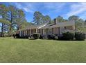 Inviting brick home with a covered front porch, lush landscaping, and a sprawling green lawn at 243 Country Club Blvd, Saint George, SC 29477