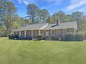 Classic brick ranch-style home featuring a covered front porch and a lush, green lawn at 243 Country Club Blvd, Saint George, SC 29477