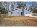 Charming blue home featuring vertical siding, well-placed windows, and an attached garage, set against a backdrop of lush trees at 4618 Moss Ct, Charleston, SC 29420