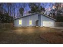 Twilight view of a cozy blue home, well-lit and nestled among trees, exudes warmth and curb appeal at 4618 Moss Ct, Charleston, SC 29420