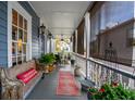 Inviting porch with a wooden bench, ferns, and rug, creating a cozy outdoor living space at 48 Montagu St # B, Charleston, SC 29401
