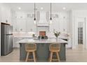 Bright kitchen features custom white cabinetry, pendant lighting, stainless appliances, and a center island with seating at 509 Rhythm St, Summerville, SC 29486