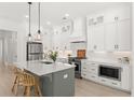 Bright kitchen features custom white cabinetry, pendant lighting, stainless appliances, and a center island with seating at 509 Rhythm St, Summerville, SC 29486