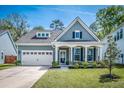 Inviting two-story home with landscaped front yard, white pillars, and black shutters at 9981 Winged Elm St, Ladson, SC 29456